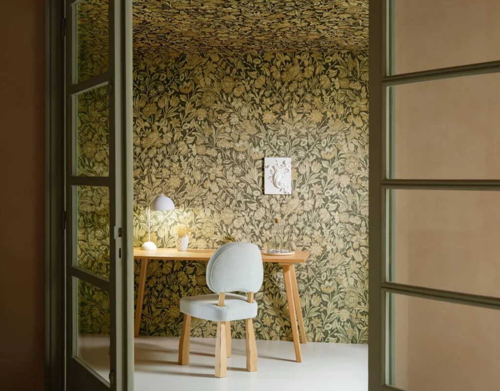 Arte Bouquet: dichtes grün-goldenes Blütenmotiv an der Wand eines kleinen Schreibplatzes.