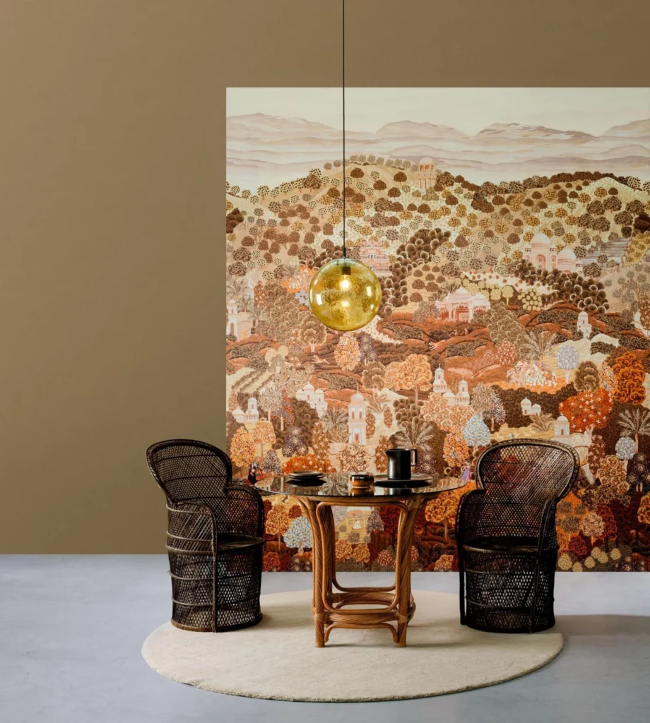 Arte Sundara: warmfarbiges Landschaftspanorama hinter einem kleinen Tisch und zwei dunklen Sesseln.