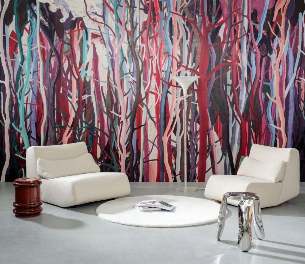 Arte Mangrove: abstrakte Baumstämme in Rot, Rosa und Blau hinter zwei weißen Sesseln.