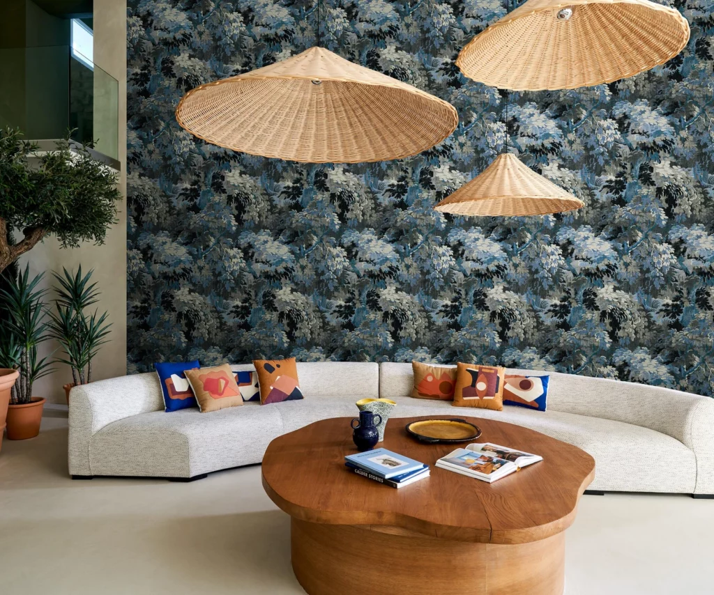 Arte Dioré: blaues botanisches Wandmotiv hinter einem gebogenen weißen Sofa und einem runden Holztisch.