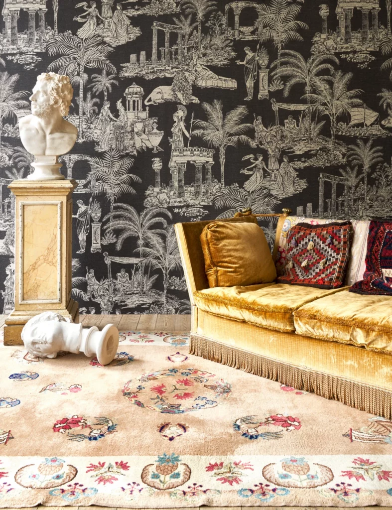 Arte Mythologie Grecque: helle Figuren und Landschaftsszenen auf dunklem Grund hinter einem goldfarbenen Sofa.