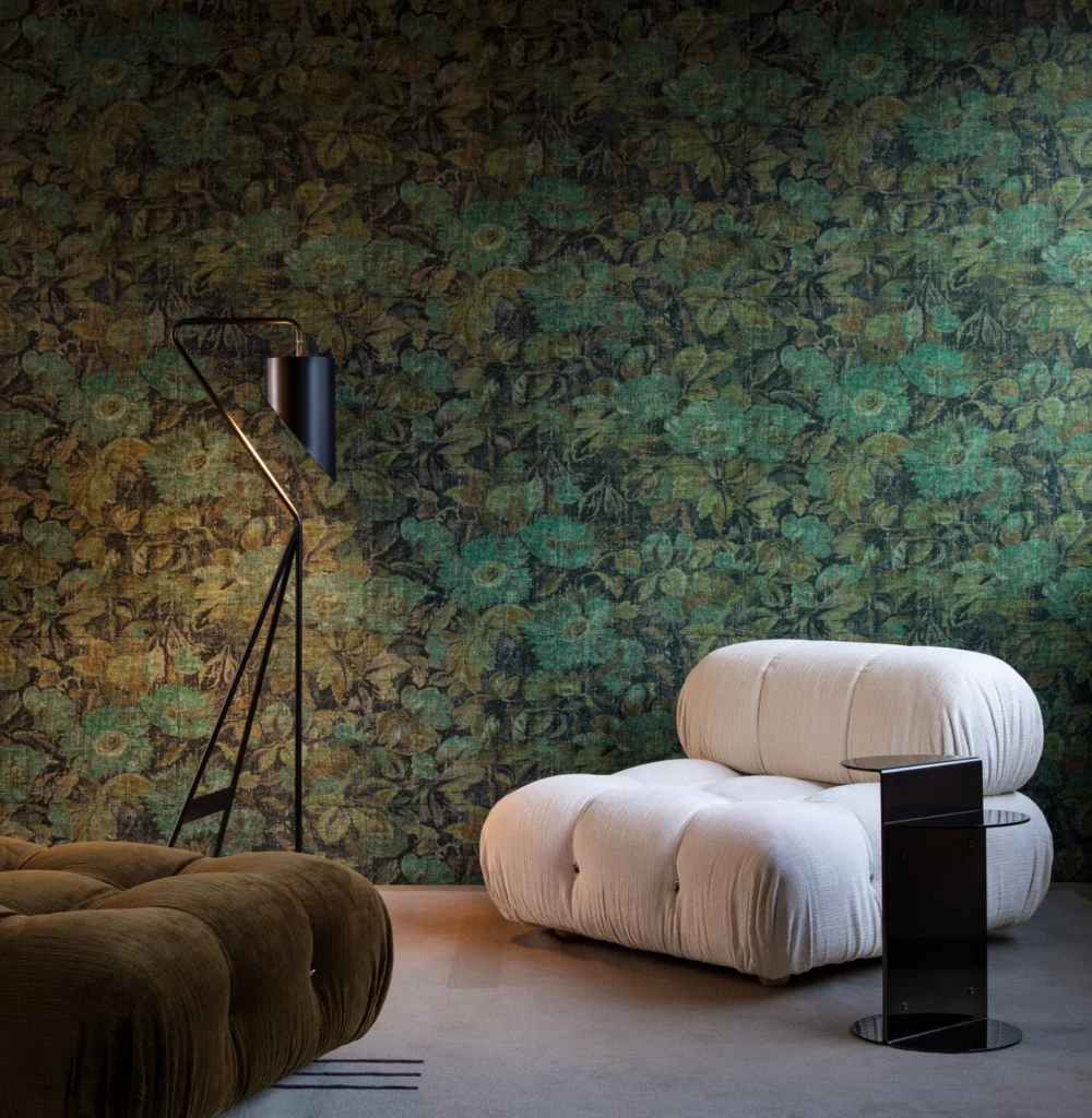 Arte Stagionato: grün-braunes Blütenmotiv in einem stimmungsvoll dunklen Wohnraum mit hellem Sessel.