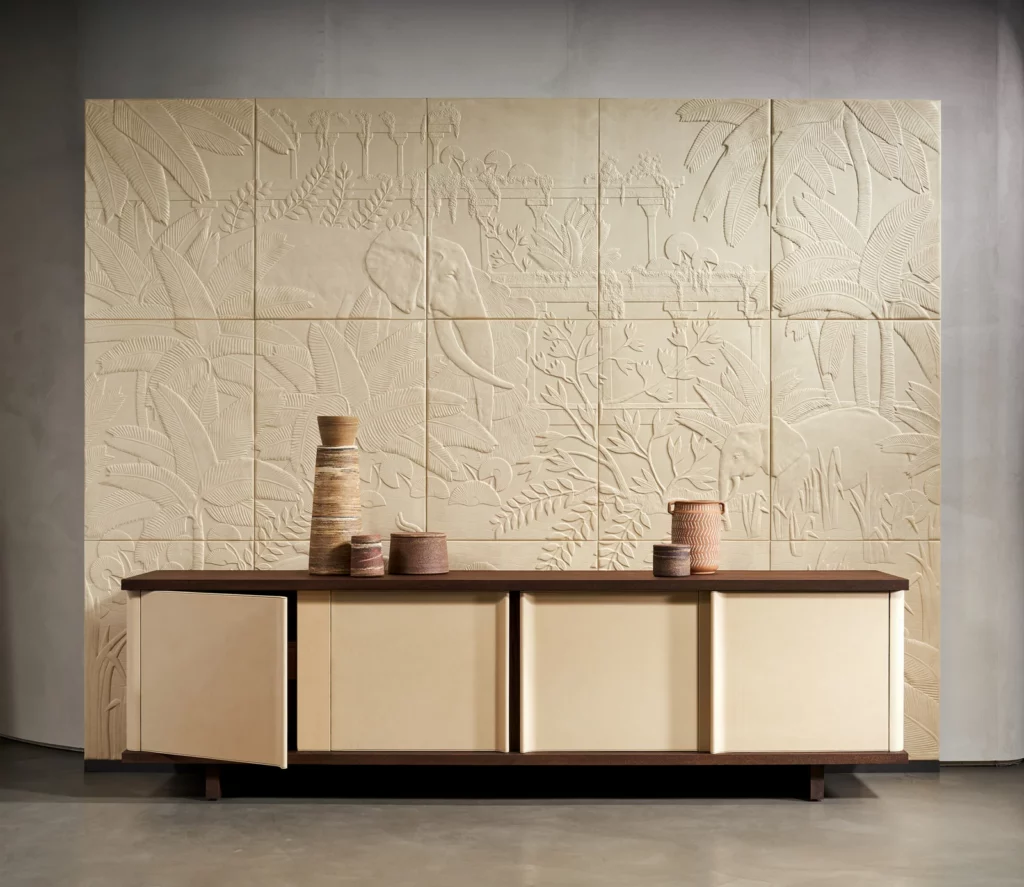 Arte Between Rivers: helles Wandrelief mit Pflanzenformen und geometrischen Linien über einem Sideboard.