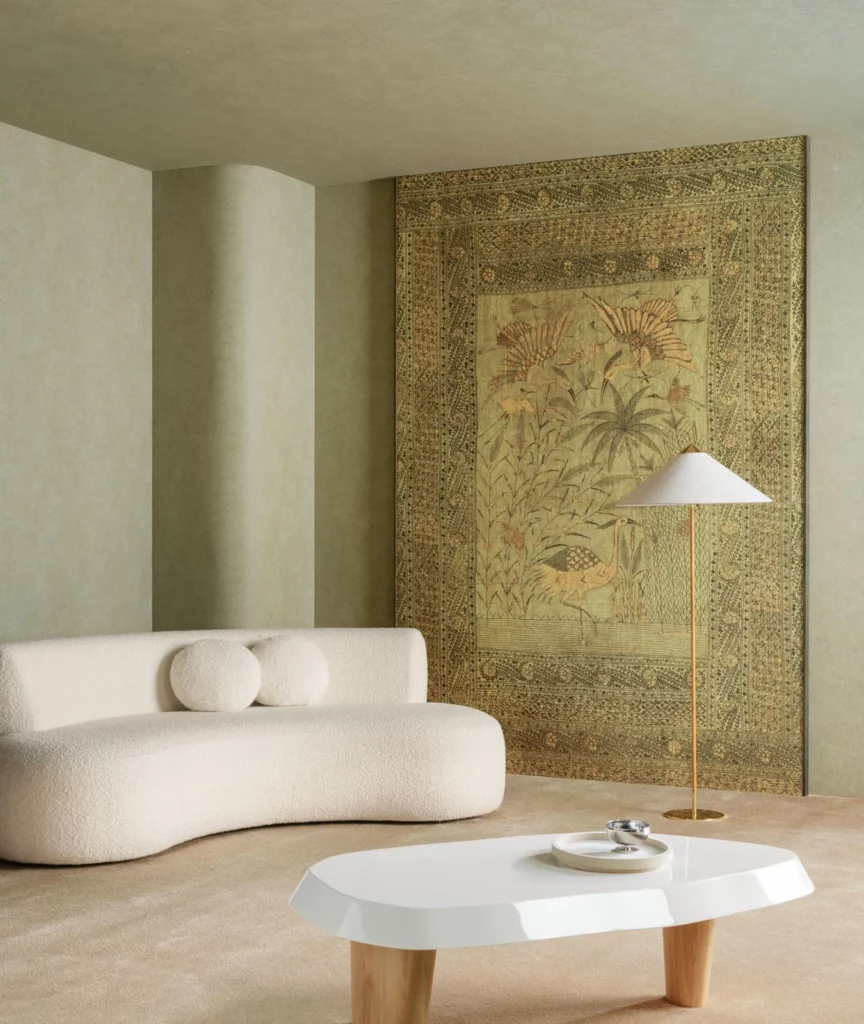 Arte Passeggio: beiges Wandbild mit verzierter Einfassung hinter einem geschwungenen weißen Sofa.