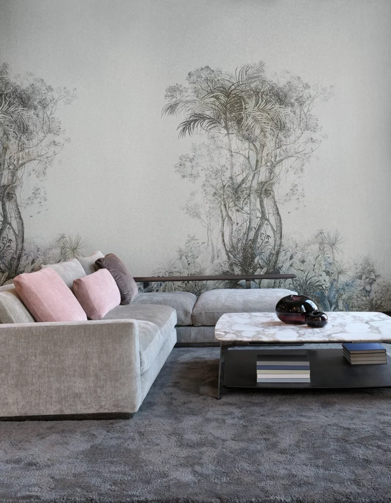 Arte Tropic: fein gezeichnete tropische Landschaft in Grau hinter einem hellen Ecksofa.