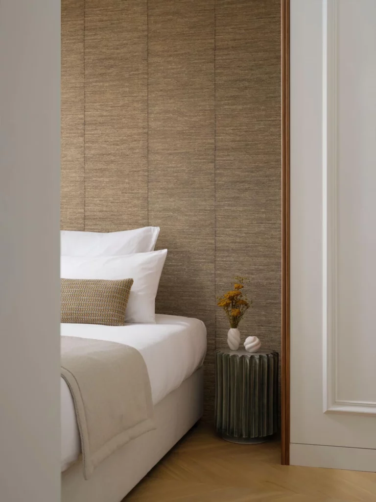 Arte Selvage: braune, textilartig strukturierte Wand hinter einem hellen Bett.