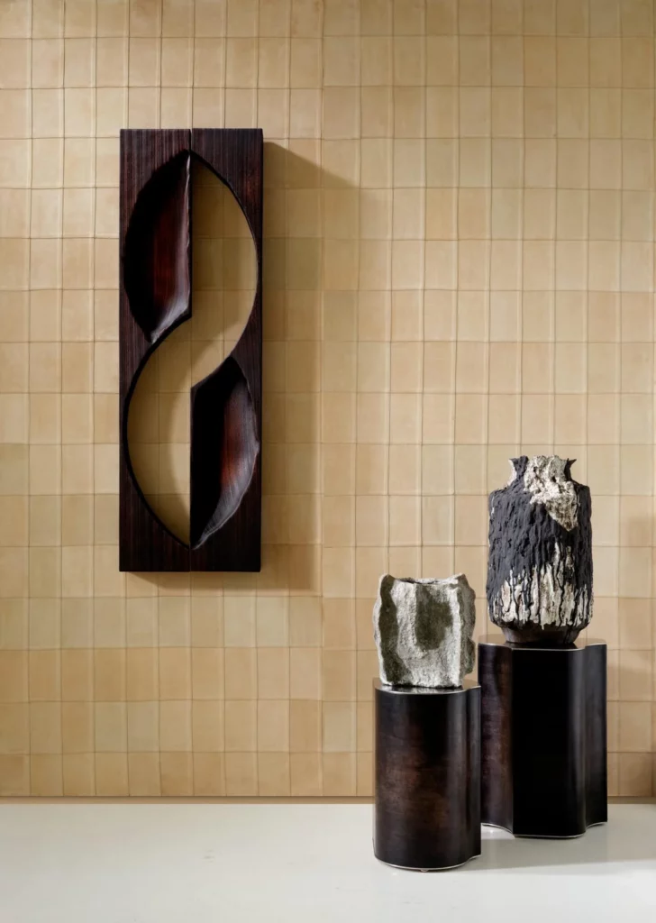 Arte Avenio: goldbeige geometrische Wandfläche mit quadratischer Gliederung hinter dekorativen Objekten.