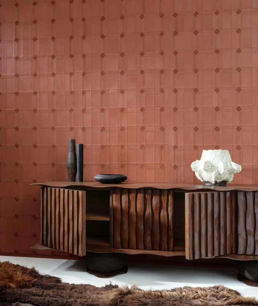 Arte Cassone: terrakottafarbene Wand mit regelmäßigen Quadraten und kleinen Ornamenten über einem Holzsideboard.