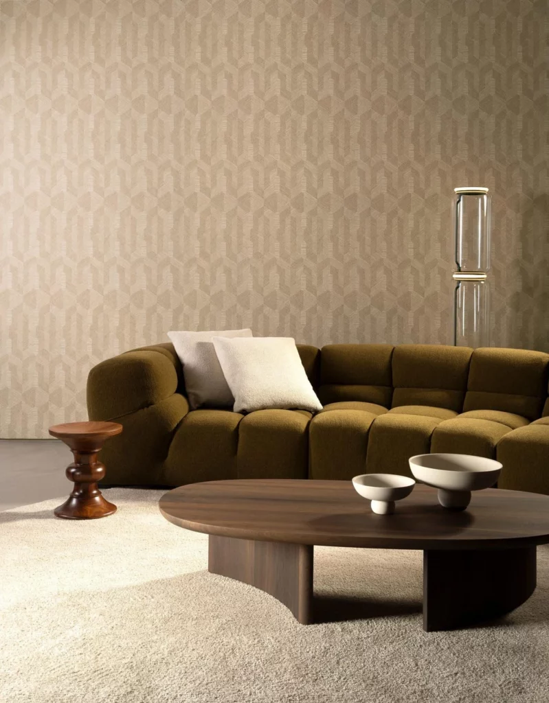 Arte Delta: helles, rhythmisches Wandmuster hinter einem olivgrünen Sofa.