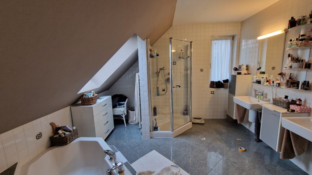 Blick auf die frühere Duschkabine und die beiden Waschbecken im gefliesten Dachgeschossbad.