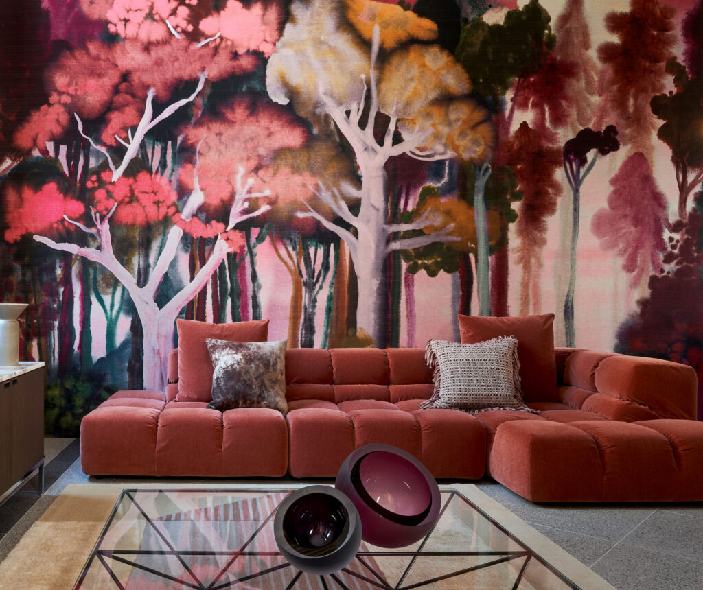 Arte Banyan: waldpanorama in kräftigen Rot- und Rosatönen hinter einem roten Sofa.