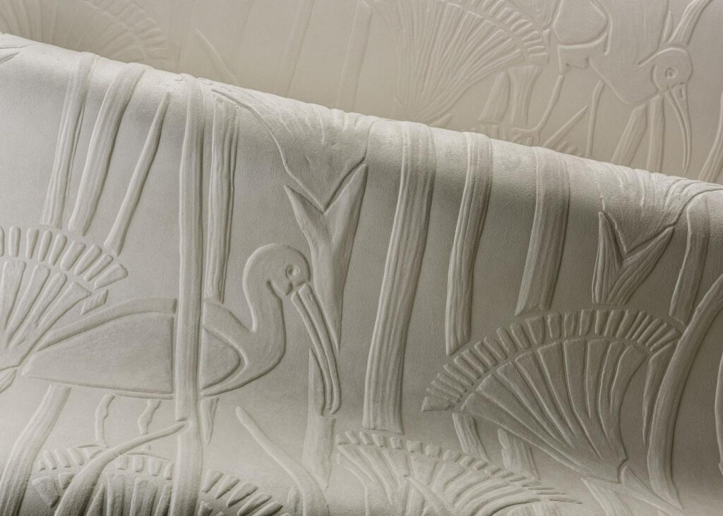 Arte Ibis: nahaufnahme des hellen Reliefs mit stilisierten Vögeln und Pflanzen.