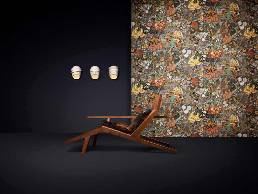 Arte Rendezvous Tokyo Blue: blüten- und Vogelmotiv in Gold- und Naturtönen auf dunklem Grund hinter einer Holzliege.