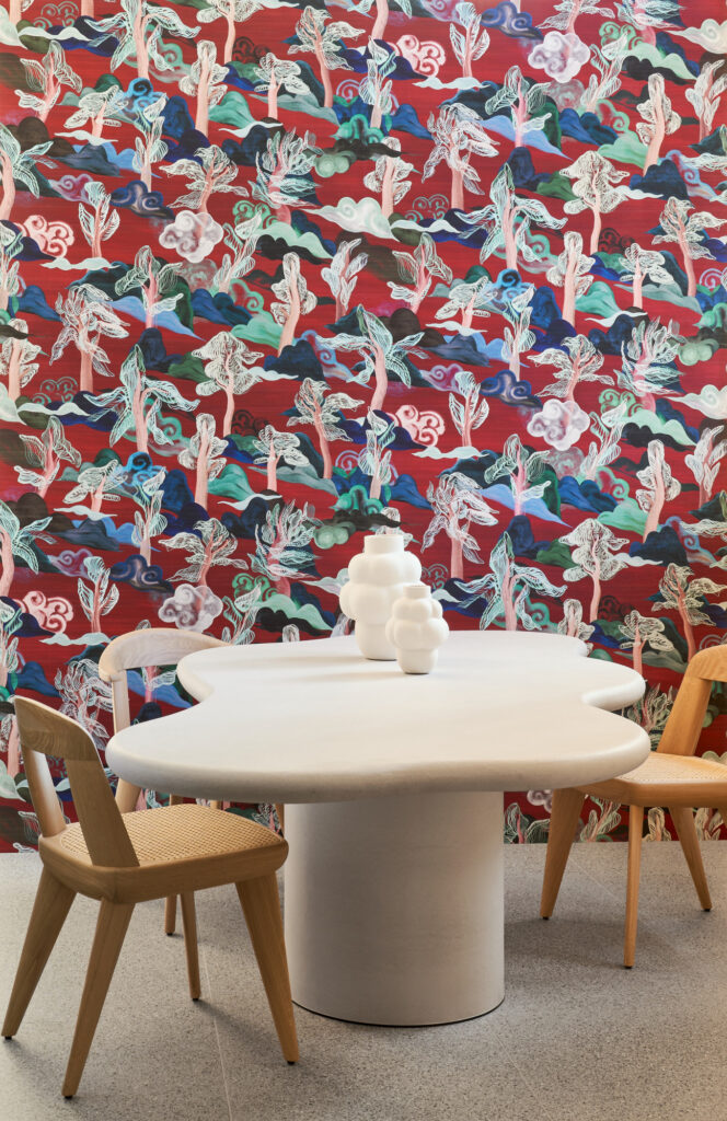 Arte Saranda: vogelmotiv in Rot-, Blau- und Grüntönen hinter einer hellen Essgruppe.