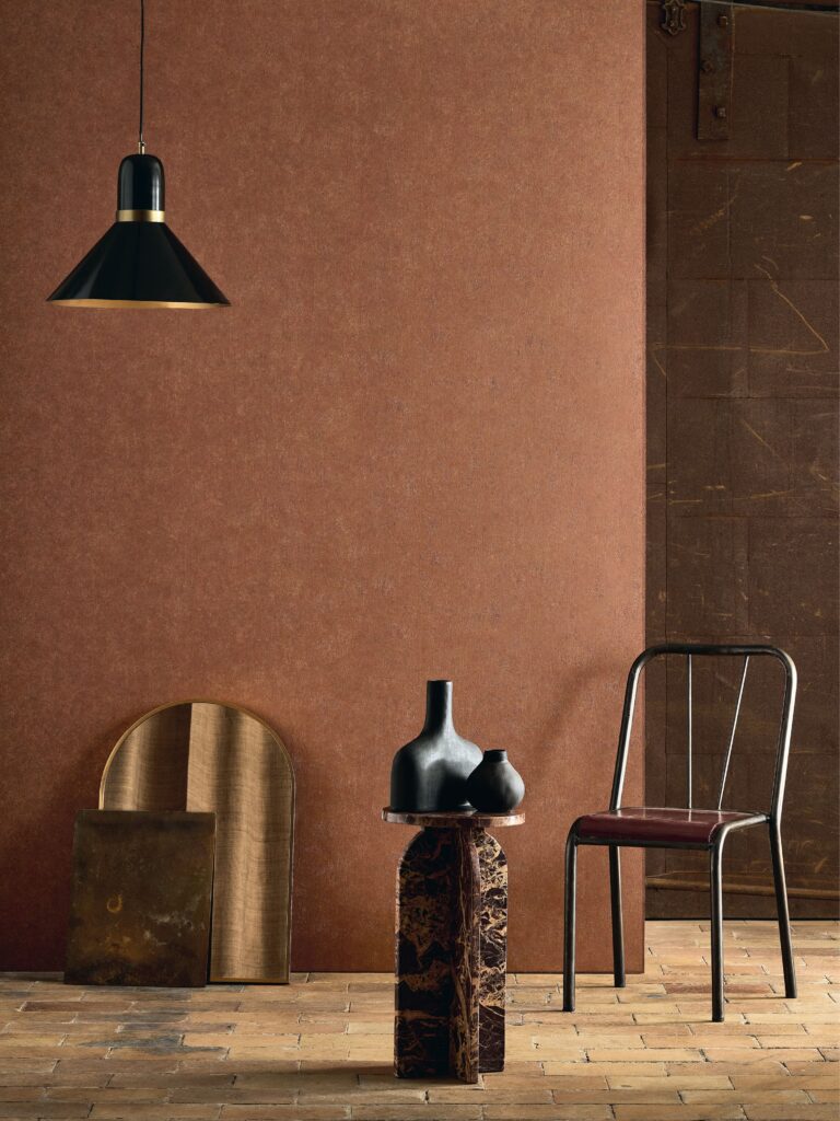 Rostbraune Wandgestaltung mit schwarzer Pendelleuchte und Metallstuhl aus der Kollektion Basalte.