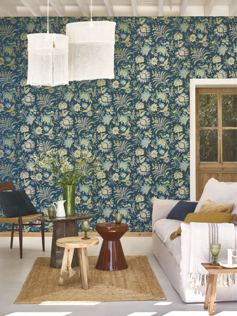 Wohnzimmer mit dunkelblauer Blumentapete, hellem Sofa und Pendelleuchten aus der Kollektion Maison de famille.
