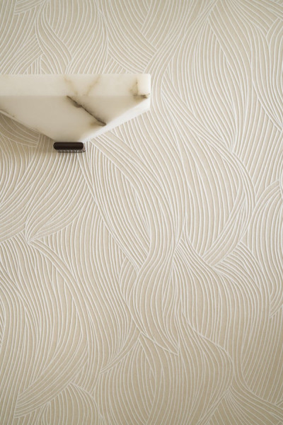 Helle Wand mit schwungvoller Linienzeichnung rund um eine weiße Wandleuchte.