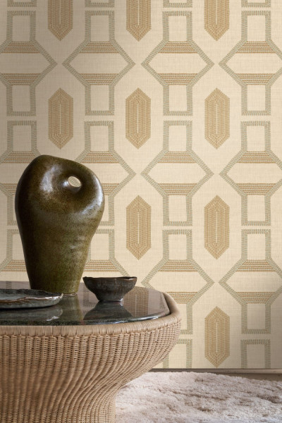 Geometrisches Wandmuster in Naturtönen hinter einem runden Flechttisch mit Keramik.