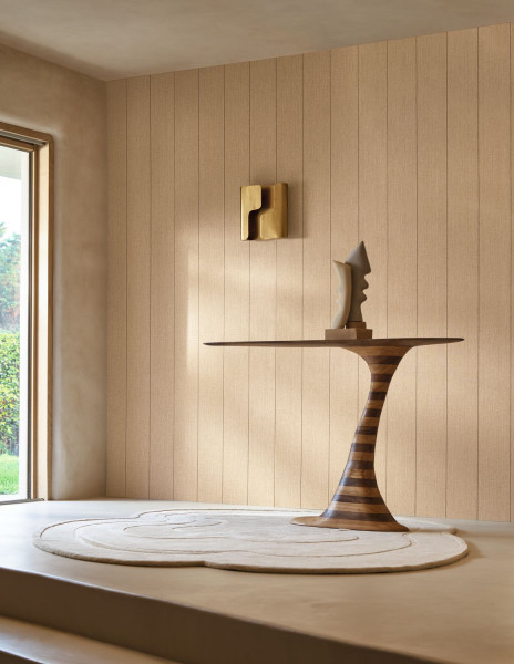Helle Wand mit feinen senkrechten Linien hinter einem skulpturalen Holztisch.
