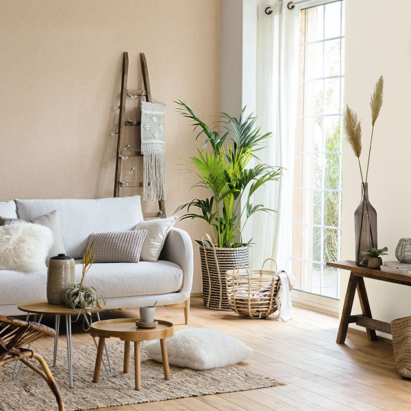 Beigefarbene ruhige Wand im Wohnraum mit hellem Sofa, Pflanzen und Naturmaterialien.