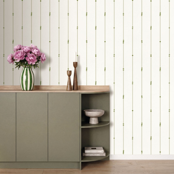 Feine grüne Linien auf heller Wand hinter einer Kommode mit rosa Blumen.