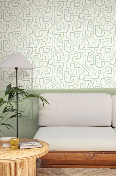 Helles grünliches Linienmuster an der Wand hinter einem weißen Sofa.
