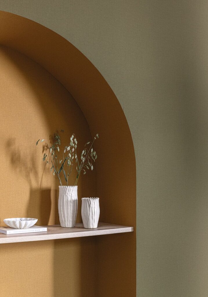 Uni-Tapeten in warmem Karamell und gedämpftem Grün an einer Wand mit gerundeter Nische.