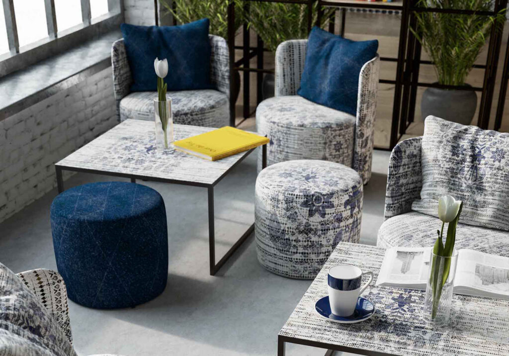 Sessel, Hocker und Tische mit grafischen Mustern und dunkelblauen Polsterakzenten.