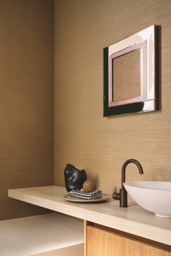 Warm beige Sisalwand hinter einem gerahmten Spiegel und einem weißen Aufsatzwaschbecken.