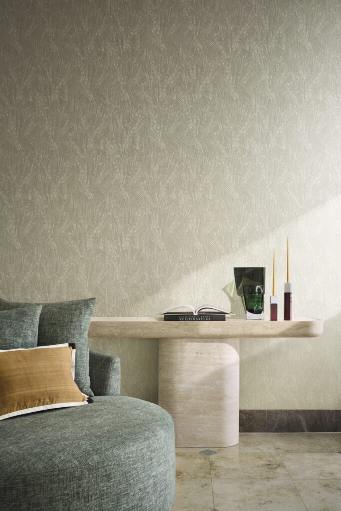 Grünliche strukturierte Wand hinter einem grünen Sessel und einer hellen steinernen Konsole.