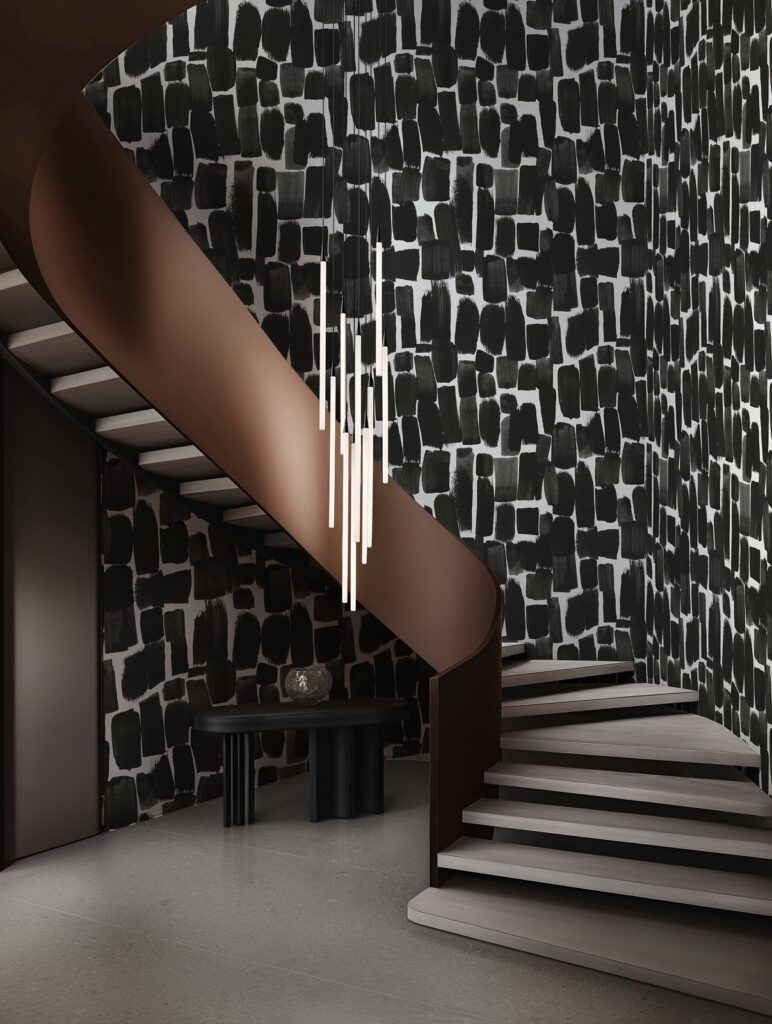 Black Attraction von Wall&decò: schwarz-weißes grafisches Muster an der hohen Wand neben einer geschwungenen Treppe.