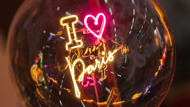 Dekorative Glühlampe mit leuchtendem Schriftzug „I love Paris“ und Herzsymbol.