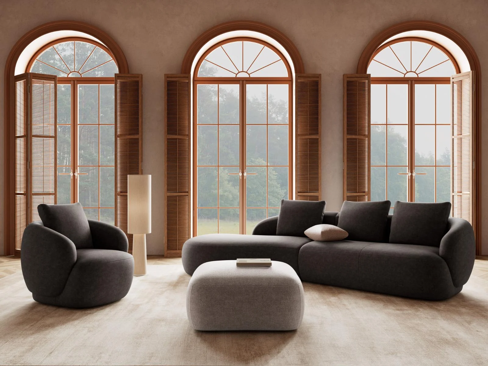 Dunkles Torino-Sofa von Flexlux mit passendem Sessel und hellem Hocker vor hohen Rundbogenfenstern.