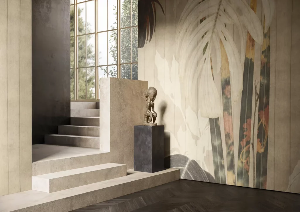 Altilis von Glamora: Große helle Blätter mit ockerfarbenen und graugrünen Flächen an einer Wand neben der Treppe.