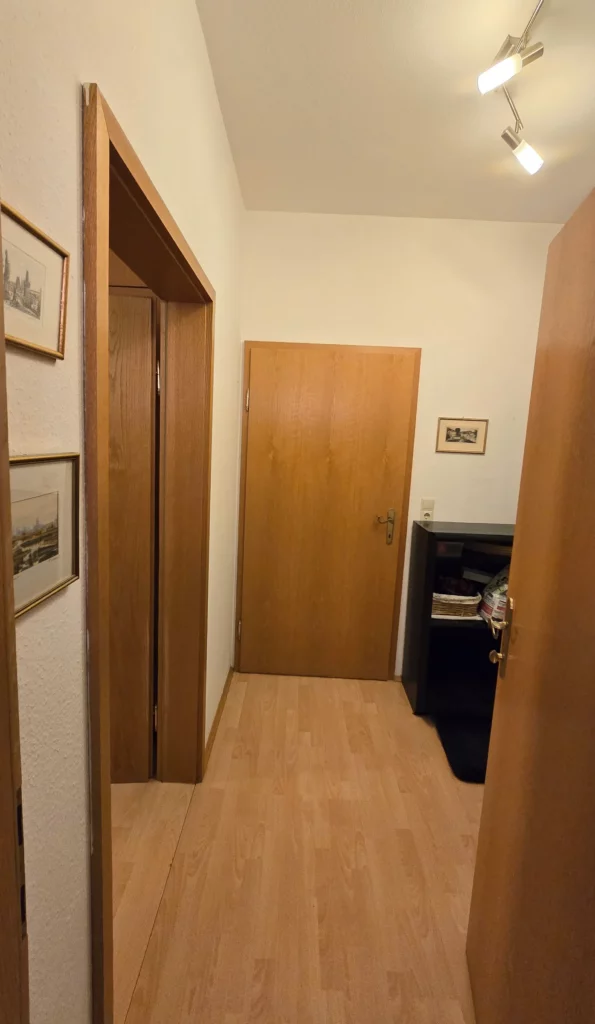 Schmaler Vorraum mit Holzboden und mehreren Türöffnungen vor dem Umbau.